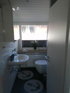 uma casa de banho com um WC, um lavatório e uma janela em Bude im Windrosenweg em Cuxhaven