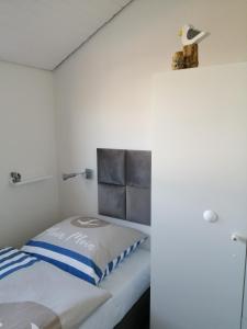 een kleine slaapkamer met een bed en een witte muur bij Bude im Windrosenweg in Cuxhaven