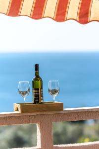 a bottle of wine and two glasses on a table at Sobe i apartman Mareta in Miholašćica