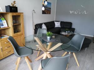 een woonkamer met een glazen tafel en stoelen bij Bude im Windrosenweg in Cuxhaven