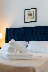 a bed with a blue headboard and a pile of towels at Art Apartment in Zadar