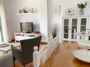 ein Wohnzimmer mit Tisch und Stühlen und einem Fernseher in der Unterkunft Disfrute de las playas y el golf en nuestro adosado en Islantilla - Costa de la Luz in Lepe