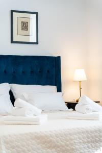 a white bed with white pillows and a blue headboard at Art Apartment in Zadar