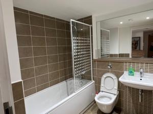ein Badezimmer mit einer Badewanne, einem WC und einem Waschbecken in der Unterkunft Modern & Spacious 2 bed Merchant City Apart-High St in Glasgow