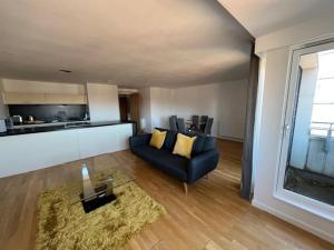 ein Wohnzimmer mit einem blauen Sofa und einem Tisch in der Unterkunft Modern & Spacious 2 bed Merchant City Apart-High St in Glasgow