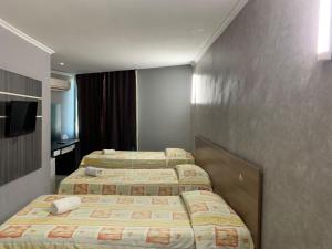 a row of four beds in a hotel room at HANNA Arcos d'Atalaia Hotel - Aracaju in Aracaju