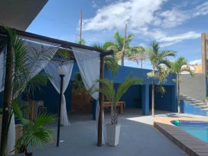 a patio with palm trees and a blue building at HANNA Arcos d'Atalaia Hotel - Aracaju in Aracaju