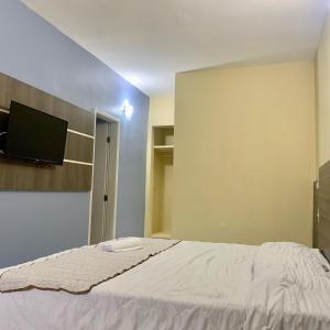 a bedroom with a bed and a flat screen tv at HANNA Arcos d'Atalaia Hotel - Aracaju in Aracaju