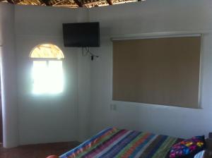a bedroom with a bed and a television on the wall at Cielito Lindo Suites in Puerto Escondido