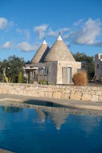 a house with a stone wall and a swimming pool at Regina di Ulivi in Ostuni