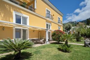 a large yellow house with a lawn in front of it at Hotel Villa Ceselle in Anacapri