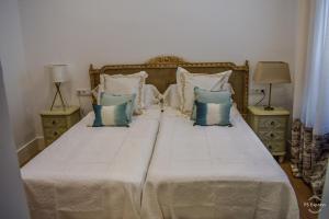 a bed with blue and white pillows on it at HOTEL LUZ ALMONASTER in Almonaster la Real