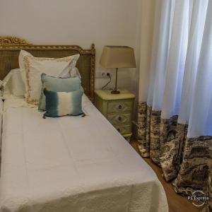 1 dormitorio con 1 cama con sábanas blancas y almohadas azules en HOTEL LUZ ALMONASTER en Almonaster la Real