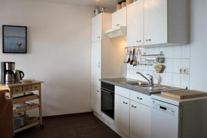 Apartment Lüdicke في Kirchdorf: مطبخ مع دواليب بيضاء ومغسلة