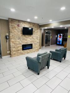 a lobby with two chairs and a tv on a brick wall at Super 8 by Wyndham South Bend in South Bend