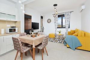 a kitchen and living room with a table and a yellow couch at Ell Star Apartment in Tivat