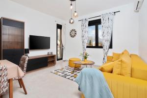 a living room with a yellow couch and a tv at Ell Star Apartment in Tivat