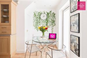 a dining room with a glass table and a clock on a wall at Modern 5 Bedroom Townhouse By City Centre & JQ - 9 Separate Beds, 2 Baths and Parking in Birmingham