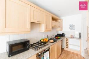 a kitchen with wooden cabinets and a black microwave at Modern 5 Bedroom Townhouse By City Centre & JQ - 9 Separate Beds, 2 Baths and Parking in Birmingham