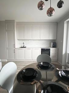 kuchnia z białymi szafkami, stołem i krzesłami w obiekcie Apartament Złote Noce w mieście Augustów