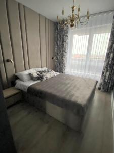 sypialnia z łóżkiem z żyrandolem i oknem w obiekcie Apartament Złote Noce w mieście Augustów