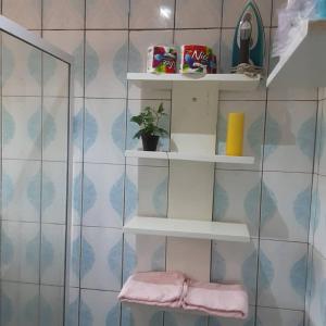 uma casa de banho com prateleiras brancas numa parede de azulejos em Color house meublée sécurisée,100m Maképé palace em Douala