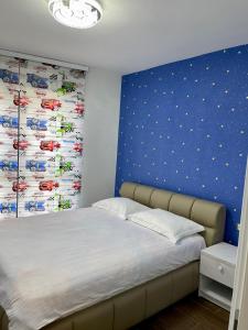a bedroom with a bed with a blue wall at Piso Moderno -Baia Mare in Baia Mare