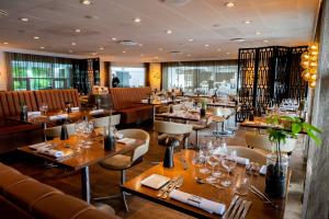 a restaurant with wooden tables and chairs and wine glasses at Hotel Svanen Billund in Billund