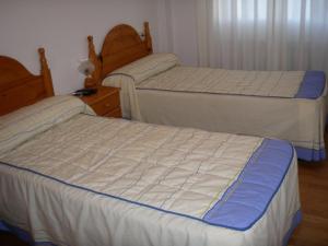 a bedroom with two beds and a dresser at Hostal la Cuesta in Vega de Espinareda