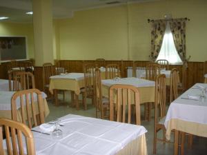 Hostal la Cuesta في Vega de Espinareda: غرفة طعام بطاولات بيضاء وكراسي خشبية
