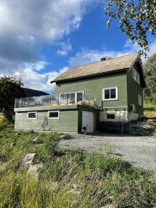 una gran casa verde sentada en la cima de un campo en Stort og autentisk hus i Skjåk - kort vei til Lom!, en Skjåk