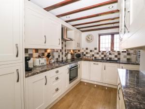 a kitchen with white cabinets and black counter tops at Burford Cottage in Weston on Avon +12 photos