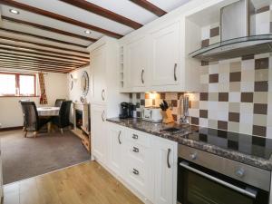 a kitchen with white cabinets and a dining room with a table at Burford Cottage in Weston on Avon