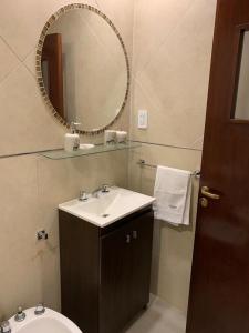 a bathroom with a sink and a mirror and a toilet at Los Naranjos Departamentos 1 in Concepción