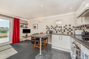 a kitchen with white cabinets and a table and a window at 16 The Boathouse in Rye