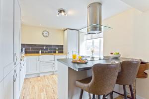 a kitchen with white cabinets and a table with chairs at Harley House in Broughton in Furness