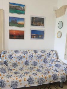 a couch in a living room with paintings on the wall at Masseria Vivi il Salento in Santa Caterina di Nardò