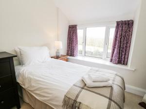 a bedroom with a white bed and a window at Groes Newydd in Llandecwyn