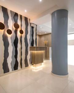 a lobby with a column and a wall with paintings at Phidias Piraeus Hotel in Piraeus