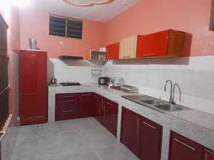una cocina con armarios rojos y fregadero en Magnifique appartement, en Cotonou
