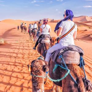 a group of people riding horses in the desert at Camp Sahara berber in Merzouga