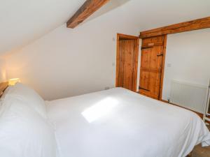 1 dormitorio con cama blanca y puerta de madera en School House Cottage, en Newtown