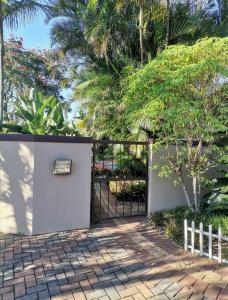 a gate to a garden with a fence and trees at The calm corner in Pinetown