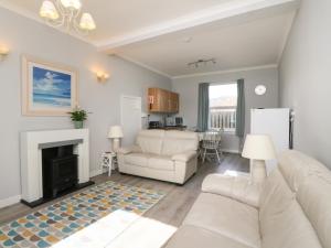 a living room with two white couches and a fireplace at The Knowe Lower in Taynuilt