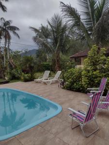 a patio with chairs and a swimming pool at Armazém do Porto Chalé Ixora in Morretes