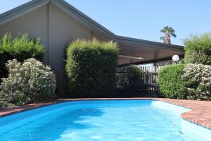 a swimming pool in front of a house at Merino Motor Inn in Saint George