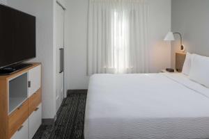a hotel room with a large bed and a flat screen tv at Sonesta Simply Suites Falls Church in Falls Church