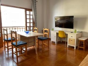 een woonkamer met een tafel, een tv en een bureau bij candelaria vacaciones centro, playa 20 metros, in center holidays beach at 20 meters in Candelaria
