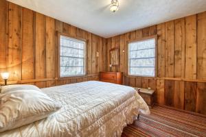 um quarto com paredes de madeira, uma cama e janelas em Tara's Dream Mountain Cabin em Canton