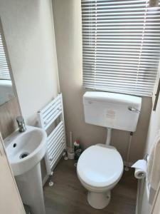 een badkamer met een wit toilet en een wastafel bij Griffiths, Seaview Caravan Park, Whitstable in Kent
